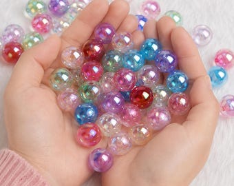 May include: A collection of round, iridescent beads in various colors including pink, blue, purple, and clear. The beads have a glossy, reflective finish and are held together in a cluster, showcasing their smooth, spherical shape and vibrant hues.