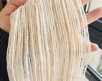 May include: A large collection of multiple long, thin strands of tiny, off-white, spherical beads. The beads are uniform in size and shape, arranged in parallel vertical lines, creating a dense, textured, and cascading appearance of light cream.