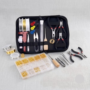 May include: A black zippered jewelry making kit containing various metal pliers, tweezers, a red caliper, a wooden-handled awl, and spools of wire. A clear plastic organizer box holds assorted gold and silver jump rings and clasps.