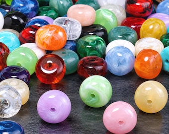 May include: A collection of round, smooth beads in a variety of colors including red, blue, green, orange, yellow, purple, pink, white, and black. Each bead features a central hole and a marbled or solid finish, creating a diverse assortment of craft supplies.