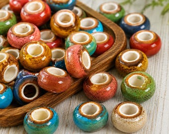 May include: A collection of round, ceramic beads with a glossy, crackled glaze finish in various colors including red, blue, green, and yellow. Each bead features a wide, white center hole and a smooth, rounded exterior surface.