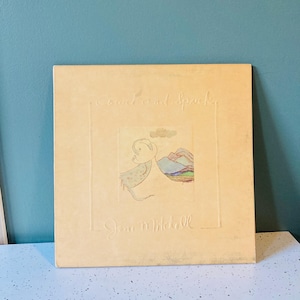 May include: A vintage album cover with the title "Touch and Spark" and the artist's name, Joan Mitchell, embossed on a beige background. The cover features a small, colorful illustration of a mountain scene and a figure.