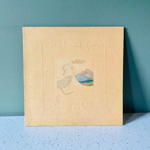 May include: A vintage album cover with the title "Cowell and Spark" embossed in a light beige color. The cover features an illustration of a figure and mountains. The artist's name, Joni Mitchell, is also embossed.