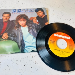 May include: A vintage vinyl record and album cover featuring Lisa Lisa and Cult Jam. The album cover shows three people, and the record is black with a Columbia label.