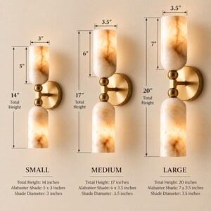 May include: Three wall sconces with cylindrical alabaster shades and brass hardware. The small sconce is 14 inches tall with 5-inch shades. The medium is 17 inches tall with 6-inch shades. The large is 20 inches tall with 7-inch shades.