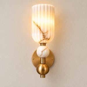 May include: A wall sconce featuring a cylindrical, fluted white marble shade with brown veining. The fixture includes a circular brass backplate, a spherical marble accent, and a spherical brass base, all connected by a central brass rod.
