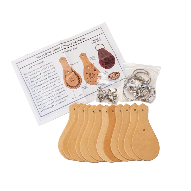 May include: A leather key fob kit with instructions and patterns. The kit includes 12 unfinished leather key fobs, metal key rings, rivets, and a stamping tool. The instructions include pattern ideas for the key fobs, such as a horseshoe, a star, and the letter K.