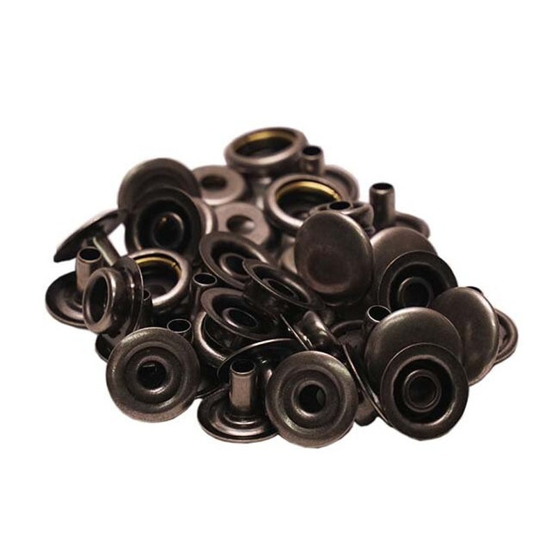 Pode incluir: Um monte de bot&otilde;es de press&atilde;o de metal preto, tamb&eacute;m conhecidos como poppers ou bot&otilde;es de press&atilde;o. Os bot&otilde;es de press&atilde;o est&atilde;o em diferentes est&aacute;gios de montagem, alguns t&ecirc;m a tampa superior presa e outros t&ecirc;m a base e o pino.