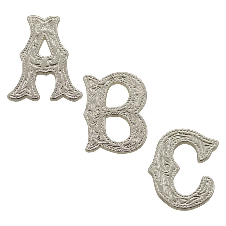 Op de afbeelding: Drie zilverkleurige metalen letters, A, B en C, met een sierlijk, bloemig ontwerp. De letters zijn in vintage stijl.