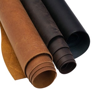 May include: Three rolls of leather in different shades of brown. The leather is rolled up and the edges are visible. The leather is a natural material and has a rustic look.