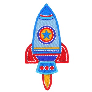 Op de afbeelding: Geborduurde patch van een raket in tinten blauw, rood en geel. De raket heeft een sterembleem en vlamdetails. De patch is ontworpen voor toepassing op kleding of accessoires.