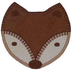 Könnte beinhalten: Braune Filzapplikation mit einem Fuchsgesicht, weißen Filzaugen und einer Nase. Das Fuchsgesicht hat braune Nähte an den Rändern und Augen.