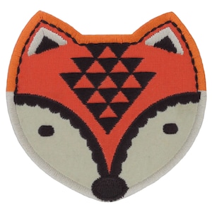 Könnte beinhalten: Ein Filz-Fuchs-Applikationen mit einem geometrischen Muster in Orange, Schwarz und Weiß. Der Fuchs hat ein weißes Gesicht mit schwarzen Augen und einer schwarzen Nase.