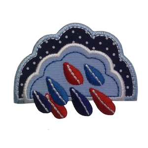 以下が含まれることがあります： 白と青の布地でできた、雲のアップリケ。雲から赤い雨粒と青い雨粒がぶら下がっている。雲は白い輪郭で、白い水玉模様で飾られている。雨粒も白い輪郭で囲まれている