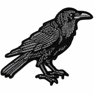 May include: An embroidered patch featuring a black raven in profile, facing right. The design uses white thread to create detailed texture on the bird's feathers, head, and beak, set against a solid black background with a stitched border.