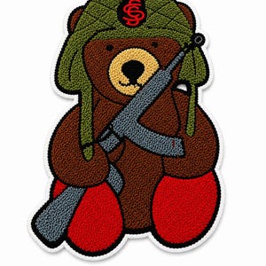 May include: A brown teddy bear patch with a textured, embroidered finish. The bear wears an olive green quilted ushanka hat with a red symbol on the front and holds a grey rifle across its chest. The bear has bright red feet and a white border.