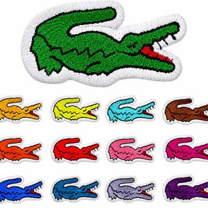 May include: A collection of embroidered crocodile patches featuring a large green version at the top and twelve smaller versions in various colors including yellow, orange, red, pink, blue, brown, purple, and light blue, all with white borders.