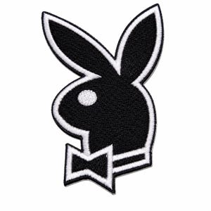 Puede incluir: Un parche bordado que presenta la icónica silueta de un conejo negro con un ojo blanco y una pajarita blanca. El diseño está delineado con un borde blanco grueso, creando un elemento gráfico de alto contraste para aplicar sobre telas.