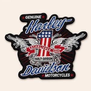 May include: A black embroidered patch featuring the text Genuine Harley-Davidson Motorcycles. The design includes a large number one with red and white stripes and blue stars, flanked by white wings and a red banner reading Established 1903.