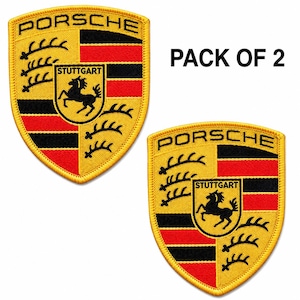 May include: A pack of 2 embroidered patches featuring the Porsche crest in yellow, red, and black. Each shield-shaped patch displays the word PORSCHE at the top, a central horse emblem with the text STUTTGART, and black antler motifs on the sides.