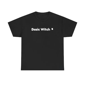 May include: A black short-sleeved t-shirt featuring the white text Basic Witch printed across the center of the chest. The garment has a crew neckline and a standard fit, showcasing a simple design with bold, clean lettering on a dark background.
