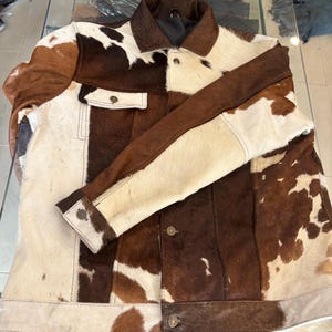 Truckerjack voor heren, gemaakt van echt rundleer met vacht in een bruin-witte combinatie, met een polyester binnenvoering.