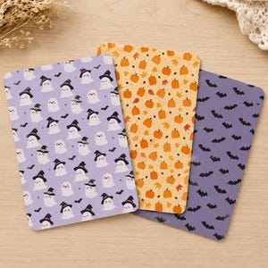 May include: Three rectangular cards featuring Halloween patterns. One card is light purple with white ghosts wearing black witch hats and small black bats. The second is orange with pumpkins and leaves. The third is dark purple with black bats.