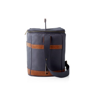 K&ouml;nnte beinhalten: Eine blaue K&uuml;hltasche aus Canvas mit braunen Lederelementen und einem Rei&szlig;verschluss. Die Tasche hat einen Schultergurt und einen Tragegriff.