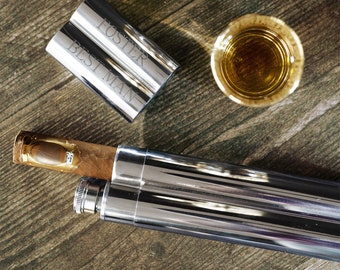 May include: A silver cigar case with a brown cigar inside. The case has a double-barrel design and is engraved with the words "Best Man" and "Foster".