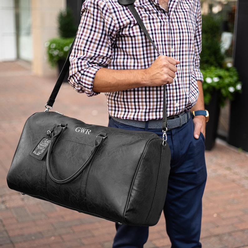 A man holding a black leather duffle bag over his shoulder