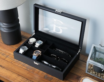 May include: A black wooden display box with a glass lid featuring a white letter B monogram. The interior is lined with black fabric and contains compartments holding three wristwatches and three pairs of sunglasses with a silver metal latch.