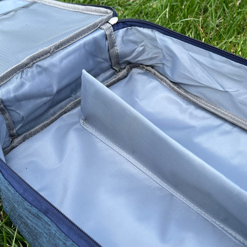 May include: A blue travel bag with a zipped opening and a grey interior. The bag has a divider inside to separate items.