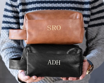 May include: Two leather toiletry bags, one brown and one black, with gold lettering. The brown bag has the initials "SRO" and the black bag has the initials "ADH".