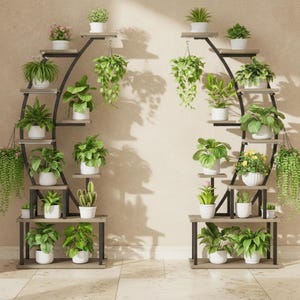 May include: Two crescent-shaped metal plant stands with multiple wooden shelves holding various potted green plants. The stands feature a curved black frame and light brown rectangular shelves arranged in a tiered, asymmetrical layout.