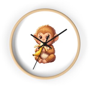 Puede incluir: Un reloj de pared redondo con marco de madera clara y esfera blanca. El centro presenta una ilustración colorida de un pequeño mono marrón peludo con ojos grandes, sosteniendo y comiendo un plátano amarillo. El reloj tiene tres manecillas negras.