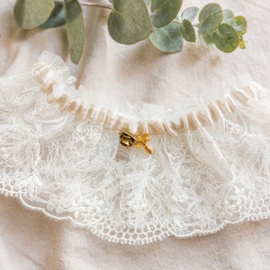 May include: White lace garter with a satin ribbon and a gold bee charm.