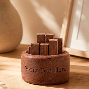 May include: A round, dark brown wooden bowl with the text "Your Text Here" engraved on the side. Inside the bowl are several small, rectangular wooden blocks of varying heights arranged in a cluster, showcasing a natural wood grain texture.