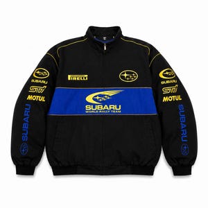 May include: A black zip-up jacket featuring a blue horizontal stripe across the chest with the Subaru World Rally Team logo. The jacket includes yellow and blue branding for Subaru, STI, Motul, and Pirelli on the chest and sleeves.