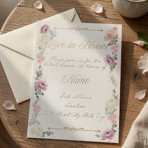 Puede incluir: Una tarjeta de invitaci&oacute;n rectangular para una despedida de soltera con un borde floral de flores rosas, blancas y azules con hojas verdes. El texto dice Love in Bloom, Please join us for the bridal shower in honor of Name, Date at Time, Location, 1234 Street City State Zip.