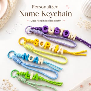 Può includere: Quattro portachiavi personalizzati con nomi realizzati in corda intrecciata e perline con lettere. Il primo è viola con il testo CUSTOM, il secondo è giallo con SOPHIA, il terzo è blu con NOAH e l'ultimo è verde con il nome LIA.