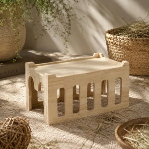May include: A rectangular light-colored wooden platform with a flat top surface and four vertical side panels featuring evenly spaced, rounded rectangular cutouts. The structure is constructed from light wood with visible grain and metal fasteners.