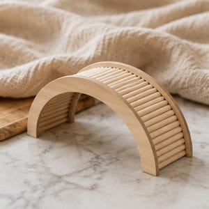 Peut inclure: Une structure de pont en bois clair dotée d'un sommet incurvé et de côtés formés par une série de tiges cylindriques parallèles. L'objet présente une finition naturelle lisse et une forme en arche semi-circulaire, révélant le grain du bois.