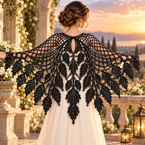May include: A black crochet shawl featuring an intricate openwork lattice pattern and a series of dangling leaf-shaped motifs along the hem. The garment is worn over a plain, light-colored dress, showcasing a detailed, dark, hand-crafted design.