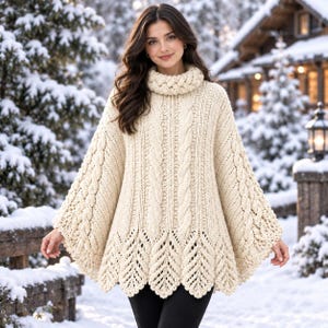May include: An off-white, cream-colored knit poncho featuring a thick, braided cable-knit turtleneck collar, vertical cable-knit patterns down the front, and a decorative, scalloped leaf-like lace hemline that drapes over the shoulders.