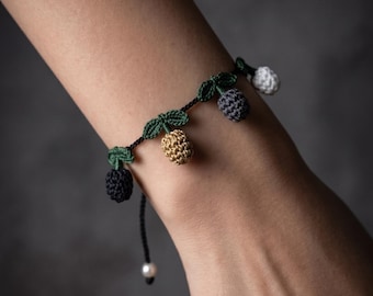 May include: A crochet bracelet featuring small, multi-colored tulip-shaped charms in black, gold, grey, and white, attached to a thin black cord with green crocheted leaves. The text "Crochet Tiny Tulip Bracelet Pattern" and "Instant PDF Download" is visible.