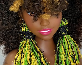 Puede incluir: Un maniquí con cabello rizado marrón y rubio que lleva largos pendientes de borla verde, amarillo y negro.