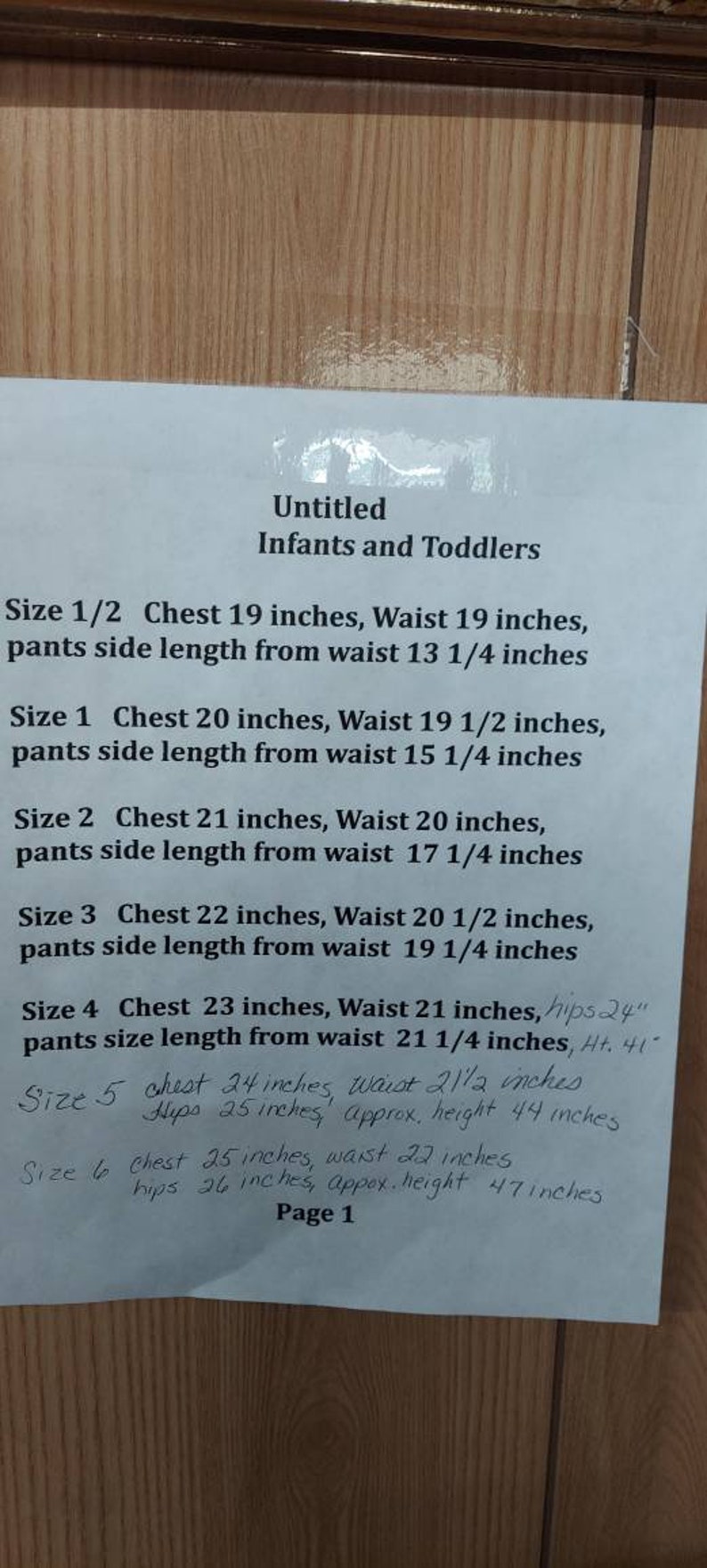 May include: A white sheet of paper with handwritten measurements for infants and toddlers clothing sizes. The measurements are in inches and include chest, waist, hips, and approximate height. The paper is titled "Untitled Infants and Toddlers" and is labeled "Page 1".