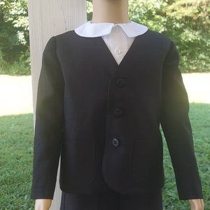 May include: A black suit with a white collar and short pants. The suit is worn by a child mannequin with brown hair.