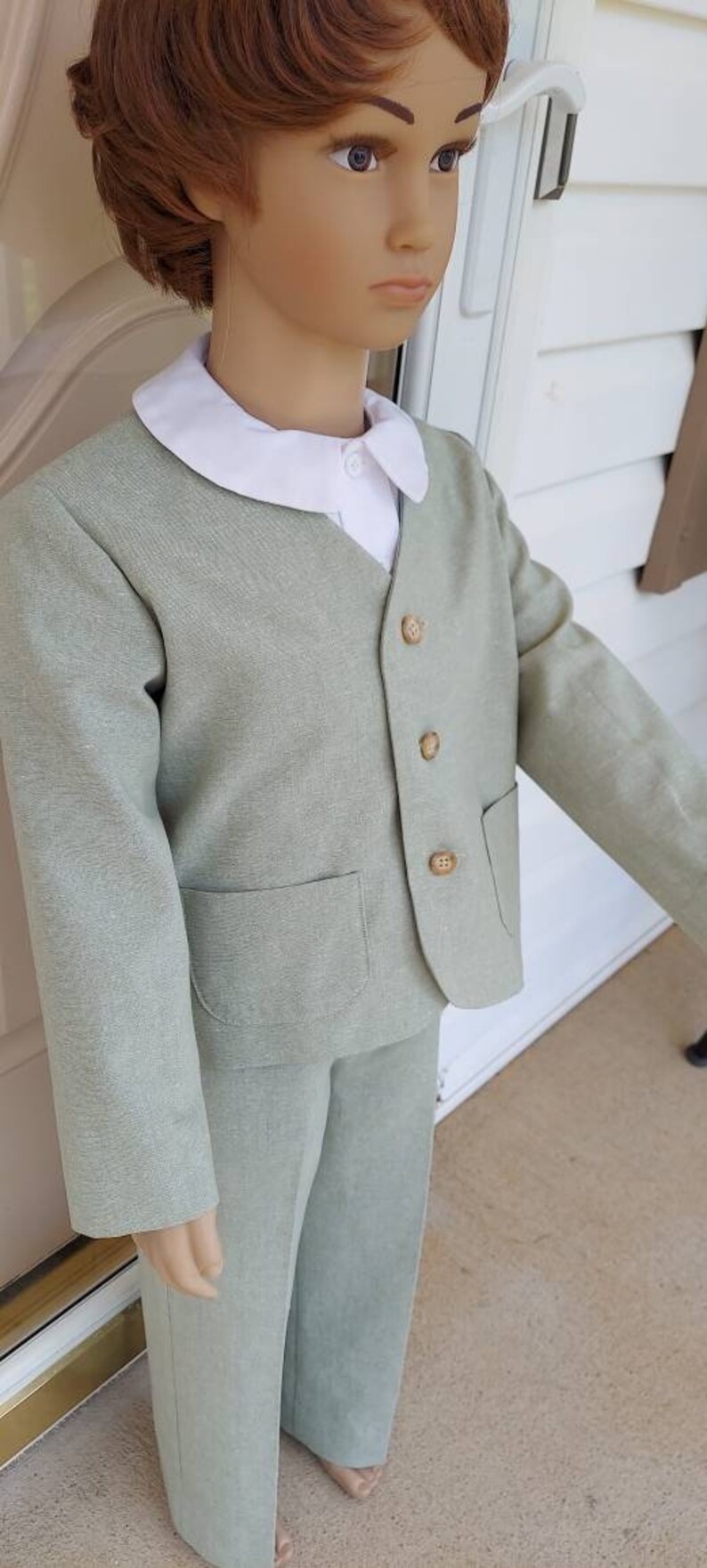 May include: A light green suit with a white collared shirt. The suit has a jacket with a pocket and buttons. The pants are long and have a straight leg.