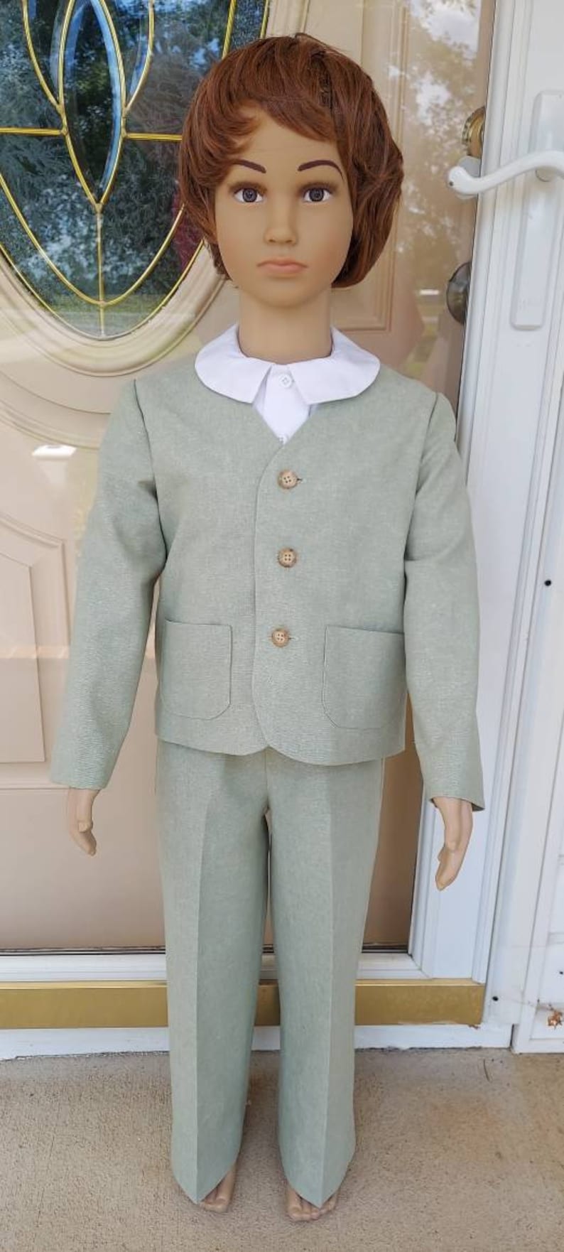 May include: A light green suit with a white collared shirt. The suit has a button-up jacket with a pocket on each side and matching pants.